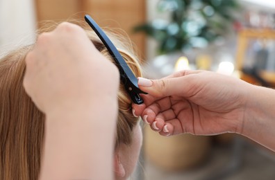 Photo of Professional hairstylist working with client in salon, closeup