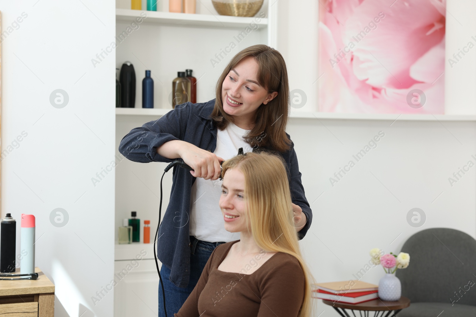 Professional hairstylist curling woman's hair in salon Photo of Professional hairstylist curling woman's hair in salon