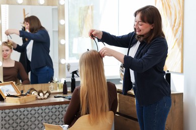 Photo of Professional hairstylist working with client in salon