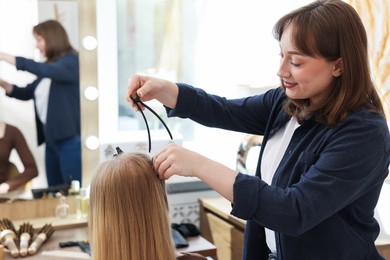 Photo of Professional hairstylist working with client in salon