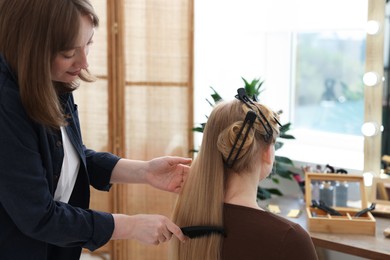Photo of Professional hairstylist combing woman's hair in salon