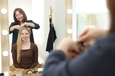 Photo of Professional hairstylist working with client in salon