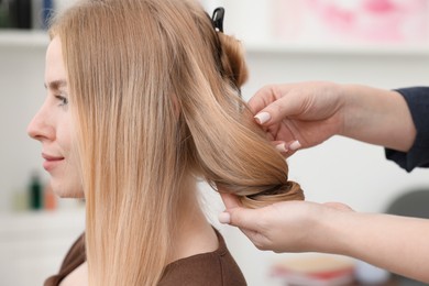 Photo of Professional hairstylist working with client in salon, closeup
