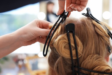Photo of Professional hairstylist working with client in salon, closeup