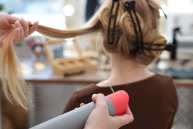 Photo of Professional hairstylist working with client in salon, closeup