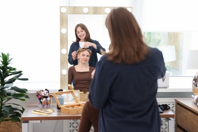 Photo of Professional hairstylist working with client in salon