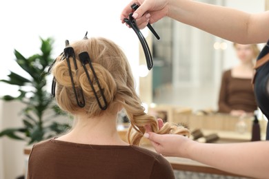 Photo of Professional hairstylist working with client in salon, closeup