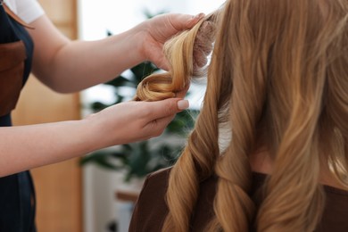 Photo of Professional hairstylist working with client in salon, closeup