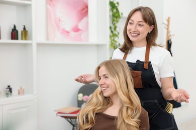 Photo of Professional hairstylist working with client in salon, space for text