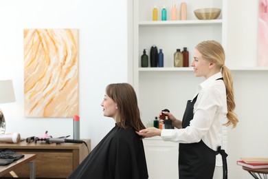 Photo of Professional hairstylist working with client in salon