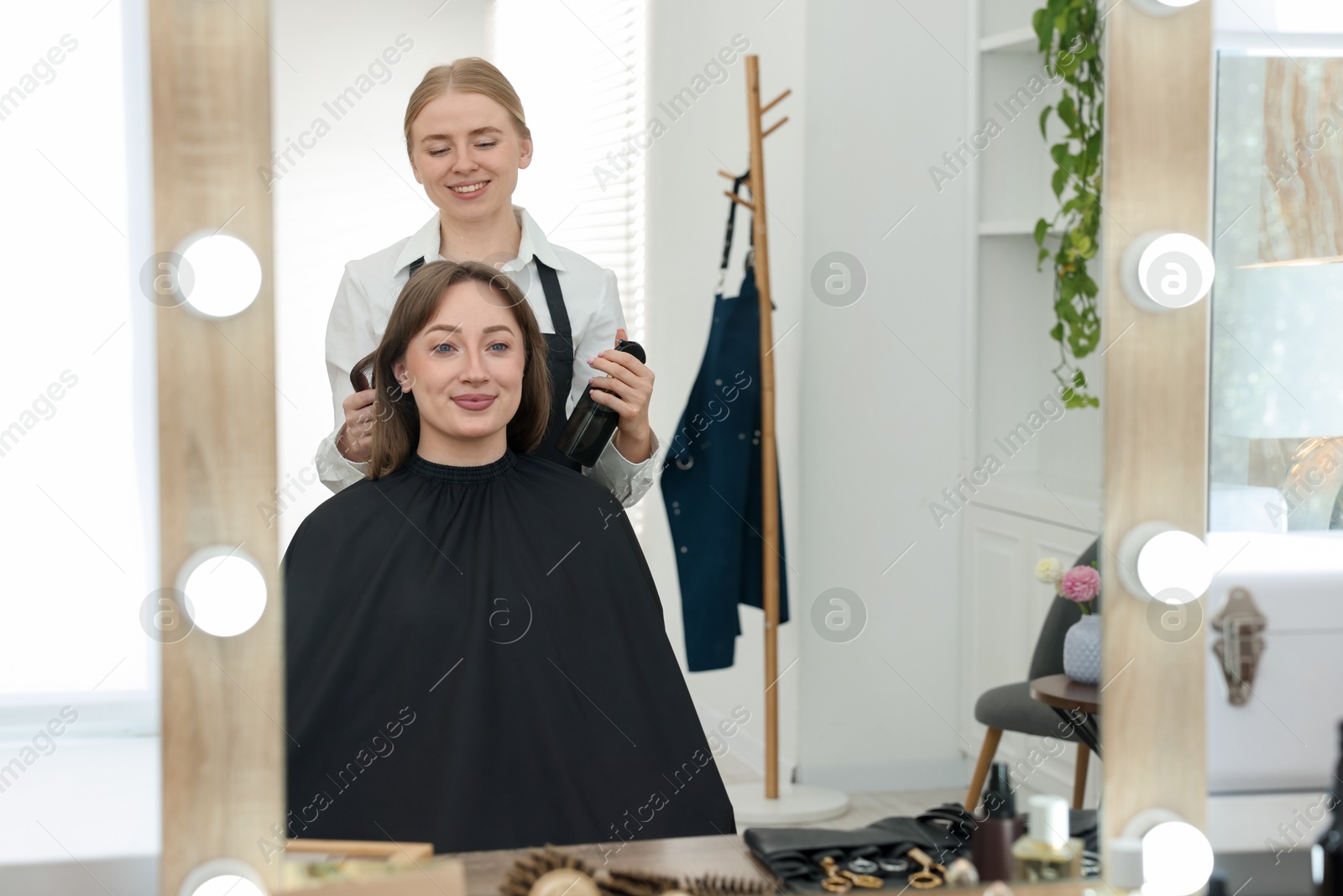 Professional hairstylist working with client in salon Photo of Professional hairstylist working with client in salon