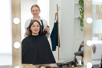 Photo of Professional hairstylist working with client in salon