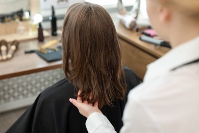 Photo of Professional hairstylist working with client in salon, closeup