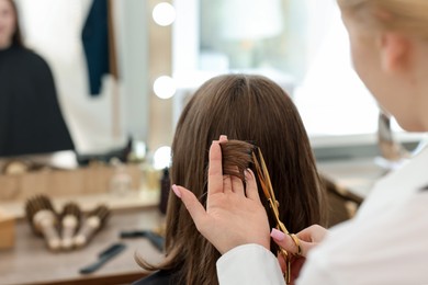 Photo of Hairstylist cutting client's hair with scissors in salon, closeup