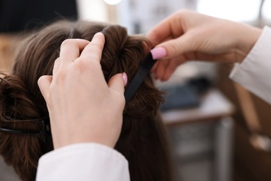Photo of Professional hairstylist working with client in salon, closeup