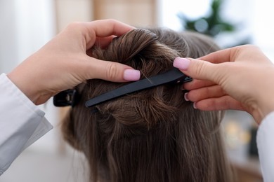 Photo of Professional hairstylist working with client in salon, closeup