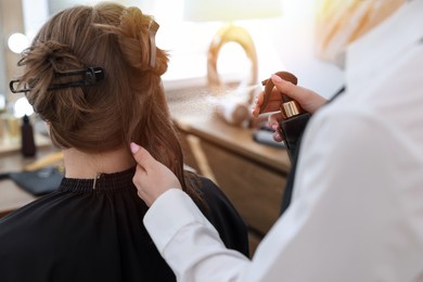 Photo of Professional hairstylist working with client in salon, closeup