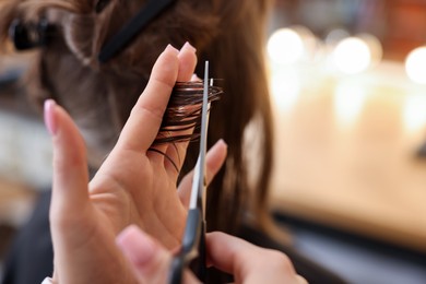 Photo of Hairstylist cutting client's hair with scissors in salon, closeup. Space for text