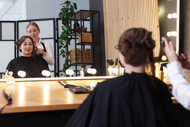 Photo of Hairstylist cutting client's hair with scissors in salon