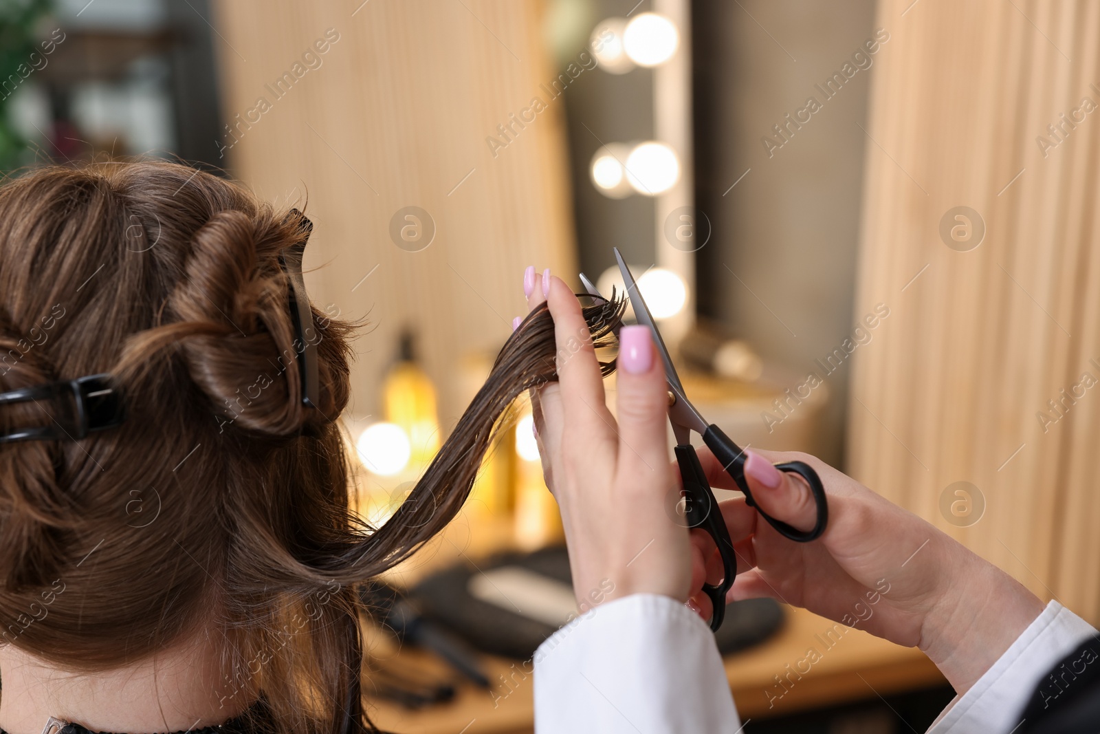 Hairstylist cutting client's hair with scissors in salon, closeup Photo of Hairstylist cutting client's hair with scissors in salon, closeup