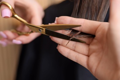 Photo of Hairstylist cutting client's hair with scissors in salon, closeup