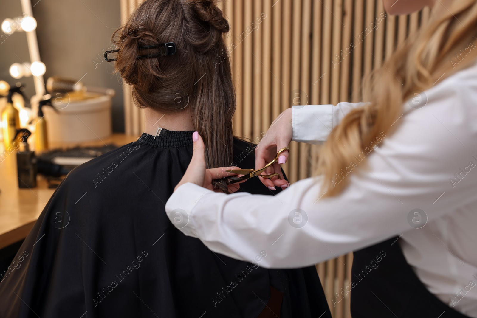 Photo of Hairstylist cutting client's hair with scissors in salon, closeup