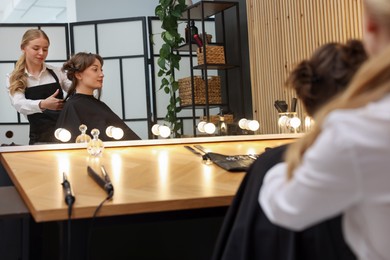 Photo of Hairstylist cutting client's hair with scissors in salon