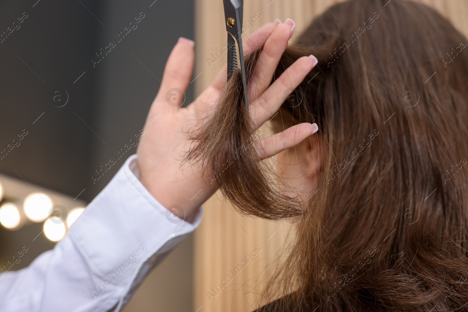 Photo of Hairstylist cutting client's hair with scissors in salon, closeup