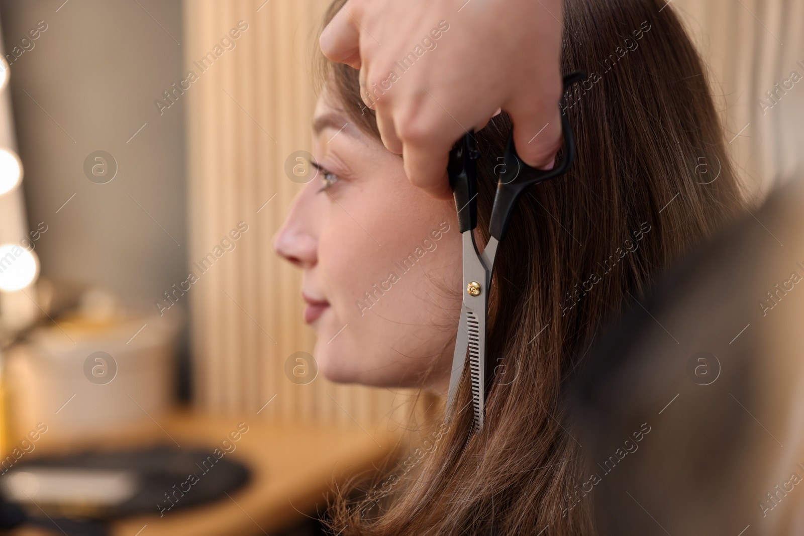 Photo of Hairstylist cutting client's hair with scissors in salon, closeup