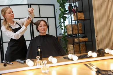 Photo of Hairstylist cutting client's hair with scissors in salon
