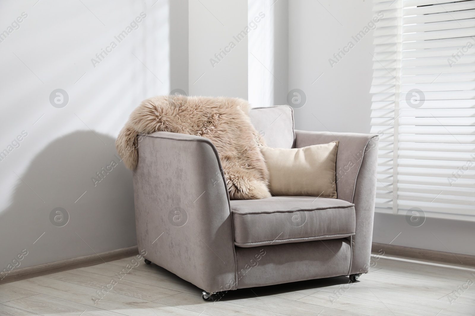 Comfortable armchair, fluffy blanket and cushion in light room Photo of Comfortable armchair, fluffy blanket and cushion in light room