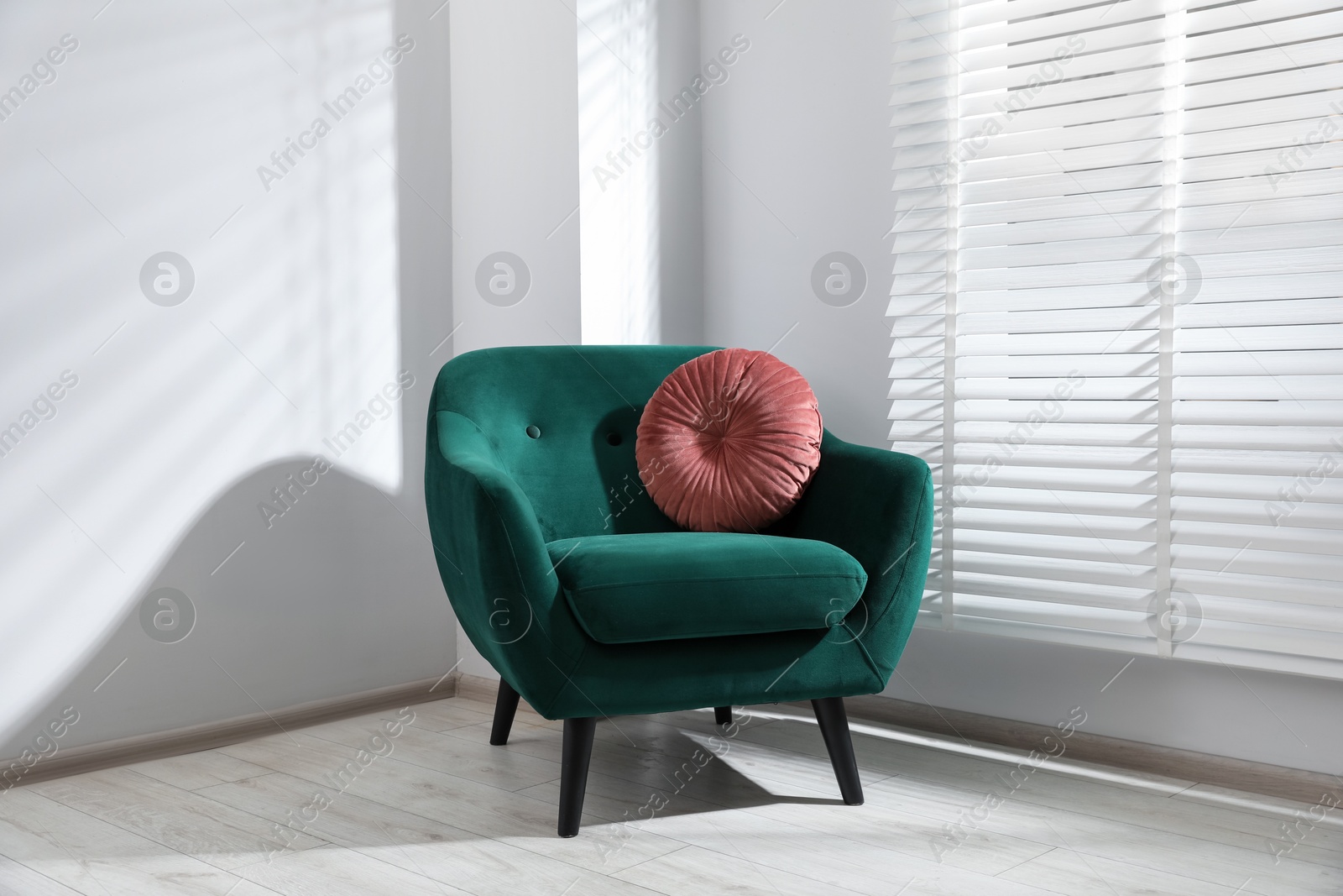Photo of Comfortable armchair and cushion near window in light room
