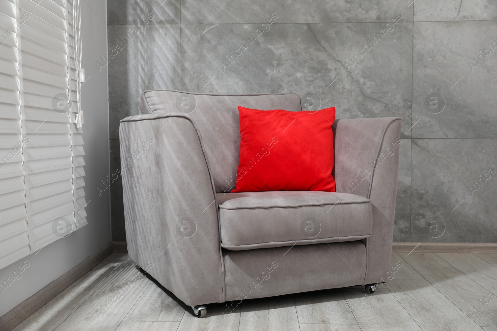 Photo of Comfortable armchair and red cushion near window indoors