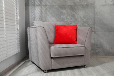 Photo of Comfortable armchair and red cushion near window indoors