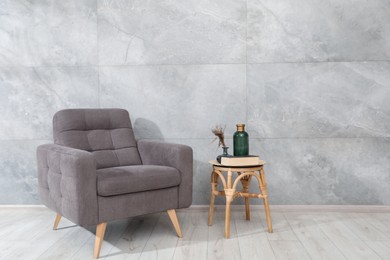Photo of Comfortable armchair and decor near gray marble wall