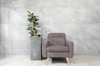 Photo of Comfortable armchair and houseplant near gray marble wall