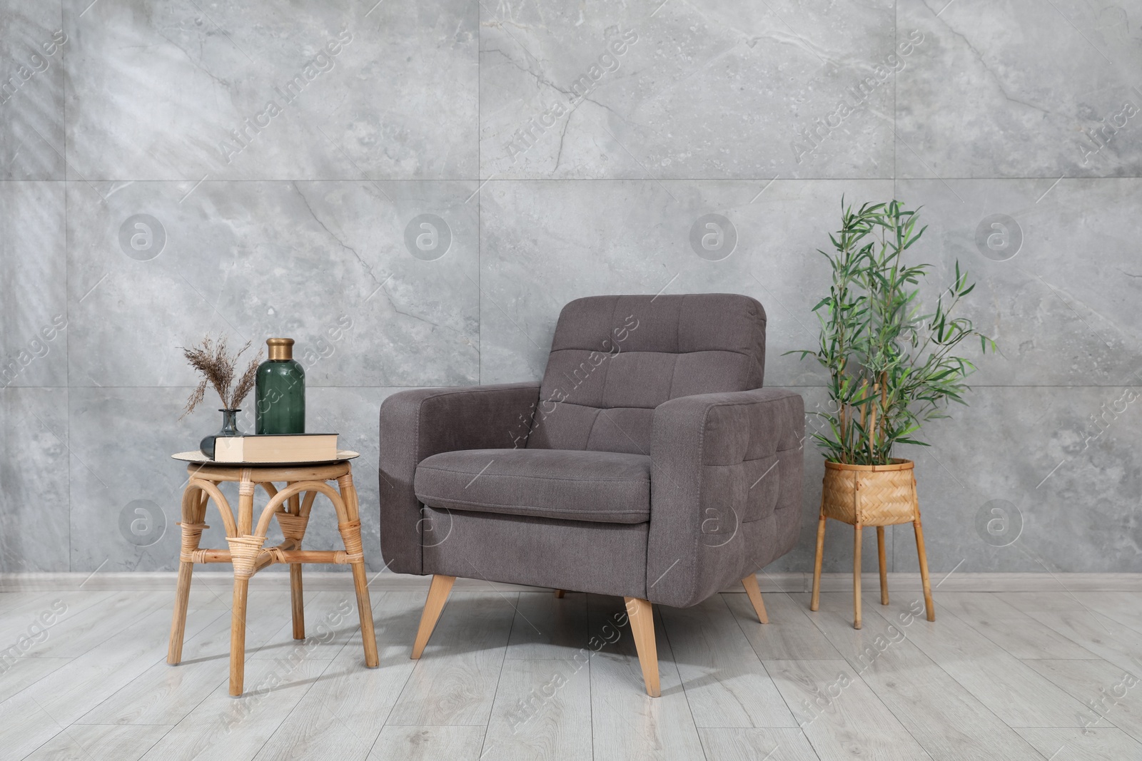 Comfortable armchair and decor near gray marble wall Photo of Comfortable armchair and decor near gray marble wall