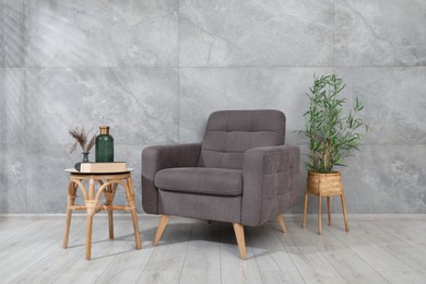 Photo of Comfortable armchair and decor near gray marble wall