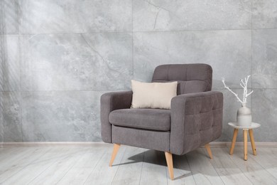 Photo of Comfortable armchair and decor near gray marble wall