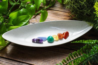 Photo of Aura. Different natural mineral stones and green leaves on wooden table, closeup