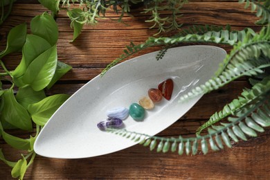 Photo of Aura. Different natural mineral stones and green leaves on wooden table, flat lay
