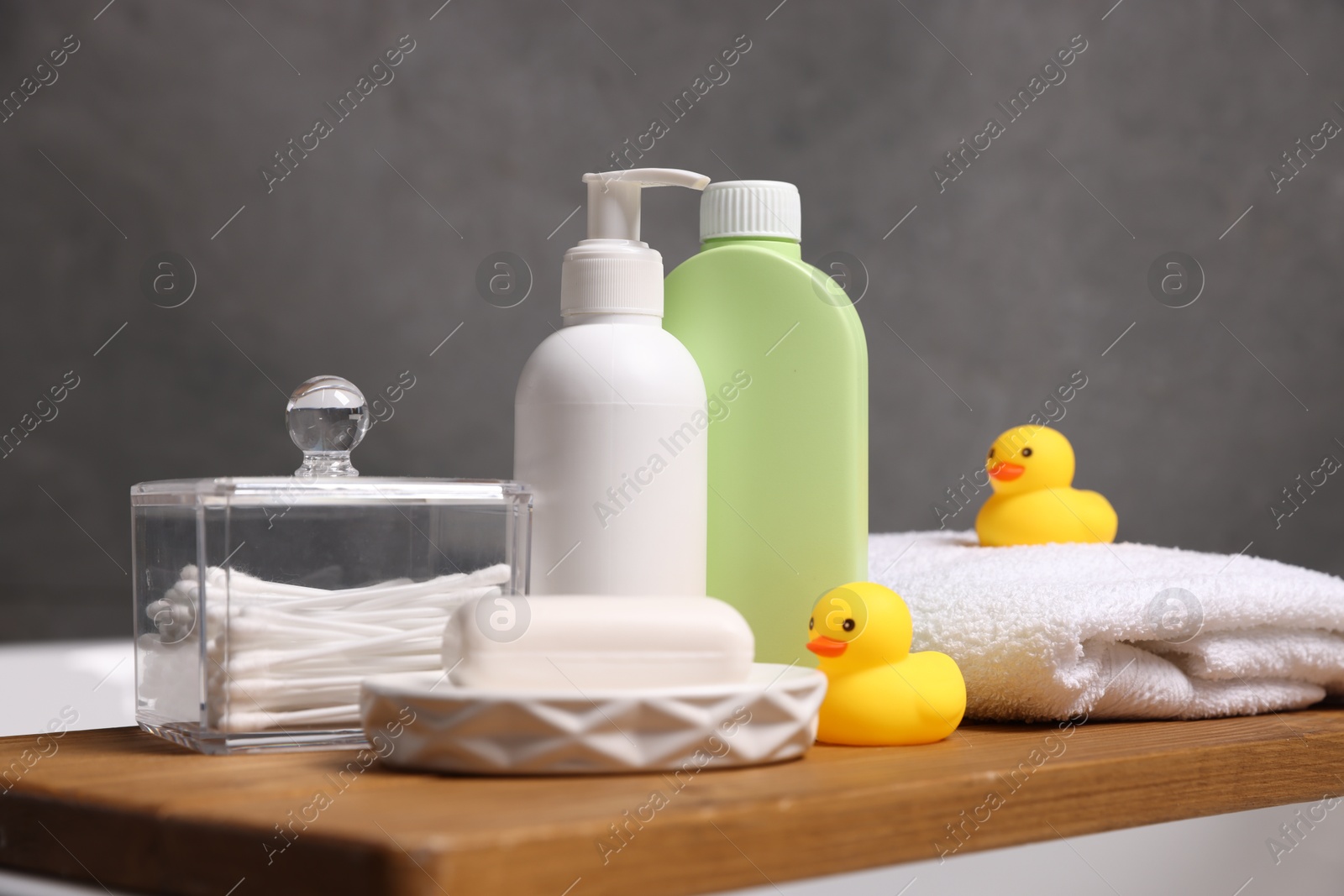 Photo of Baby accessories and bathing products on wooden tray in bathtub indoors, closeup
