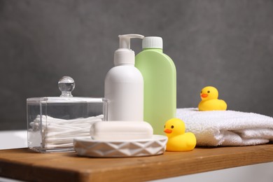 Photo of Baby accessories and bathing products on wooden tray in bathtub indoors, closeup