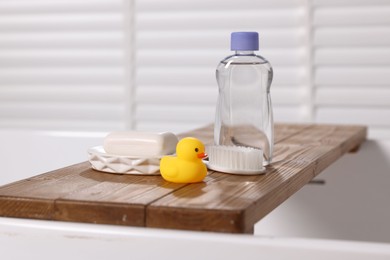 Photo of Baby bath accessories on wooden tray in bathtub indoors, closeup
