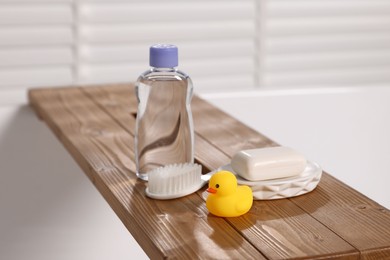 Photo of Baby bath accessories on wooden tray in bathtub indoors, closeup