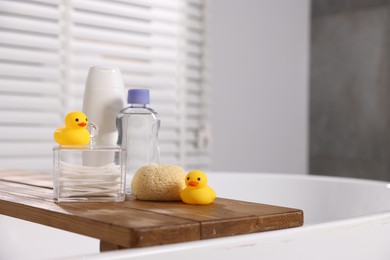 Photo of Baby accessories and bathing products on wooden tray in bathtub indoors, closeup. Space for text