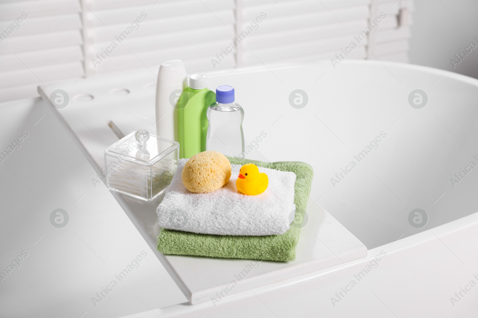 Photo of Baby accessories and bathing products on tray in bathtub indoors