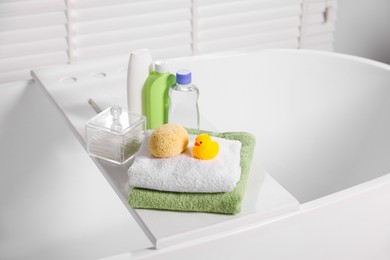 Photo of Baby accessories and bathing products on tray in bathtub indoors
