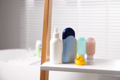 Photo of Baby bathing products and rubber duck on rack in bathroom, closeup