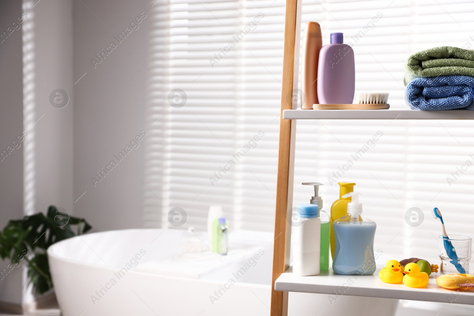 Photo of Baby accessories and bathing products on rack in bathroom. Space for text